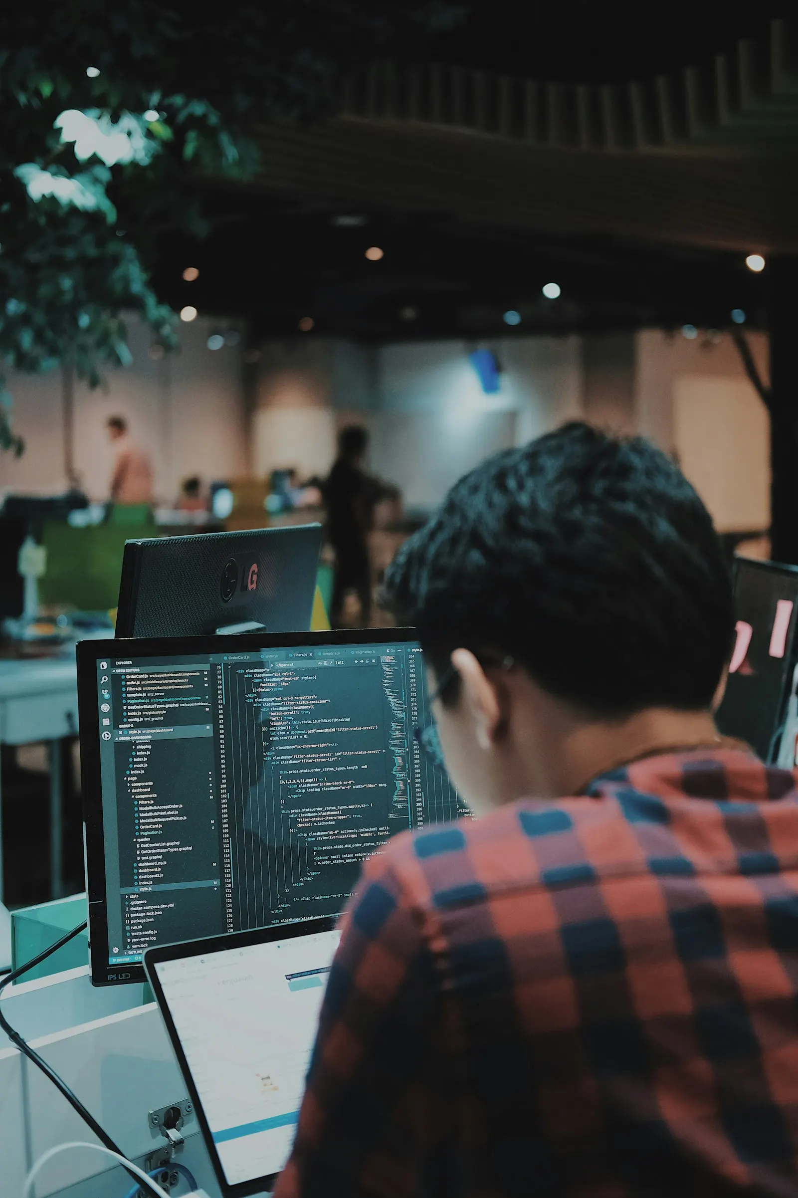 A nearshore DevOps engineer in Canada works at a monitor in an open office.