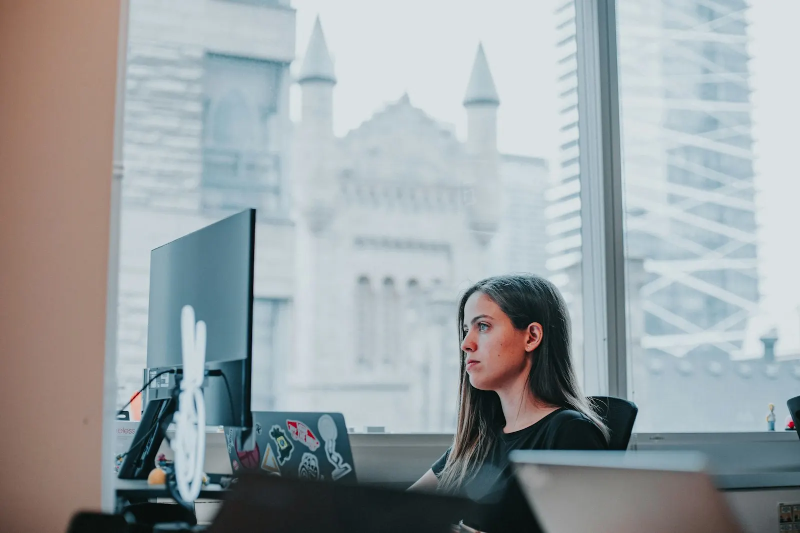 A nearshore developer in Canada works at her desk by a tall office window.