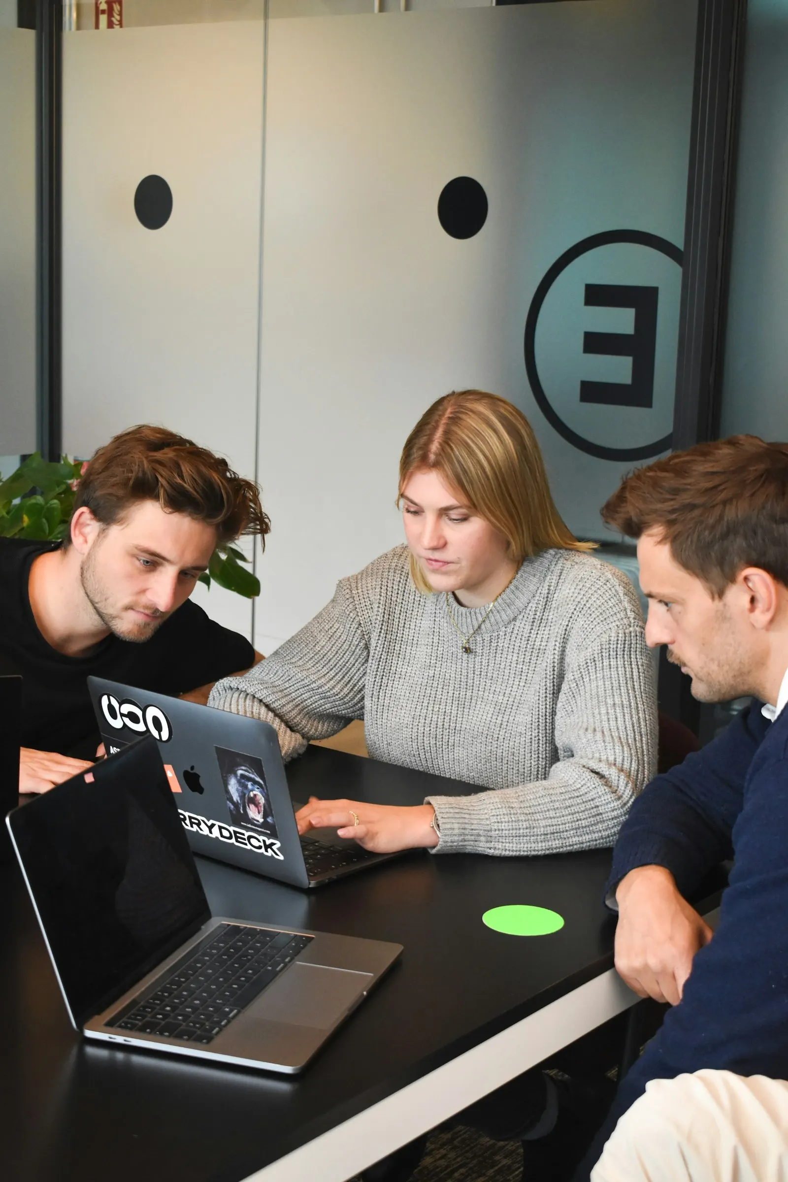 Three nearshore developers in Canada work through a problem together on one laptop.