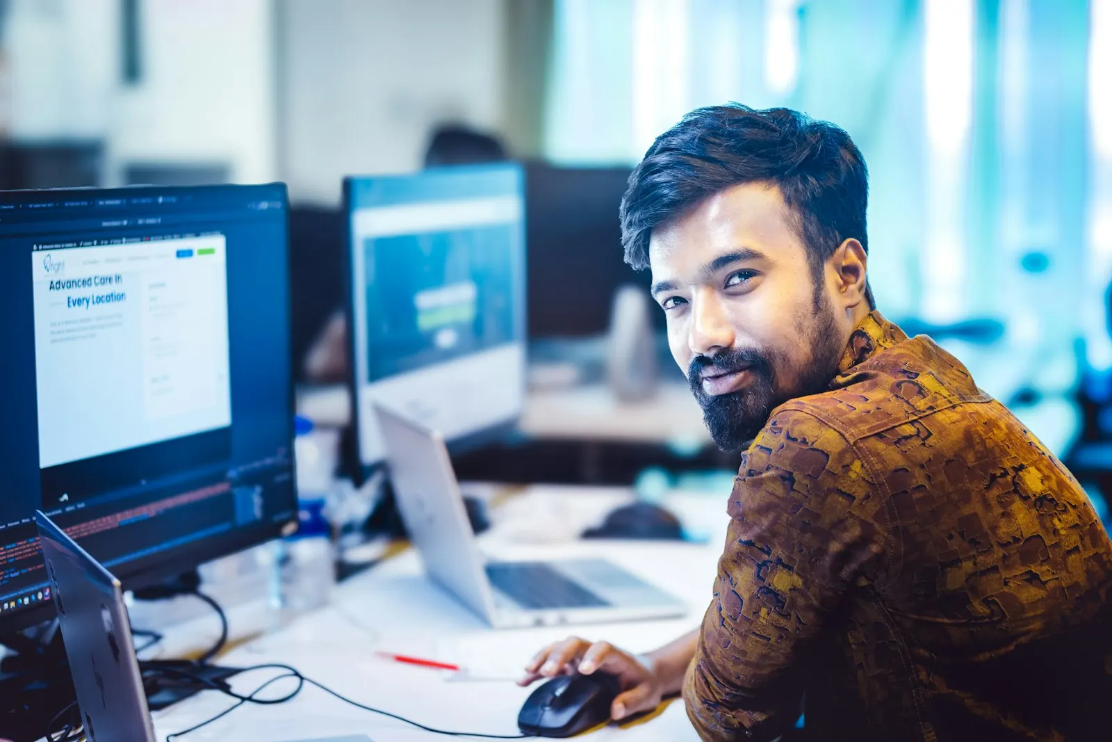 An offshore DevOps engineer in India looks up from a desk of screens.