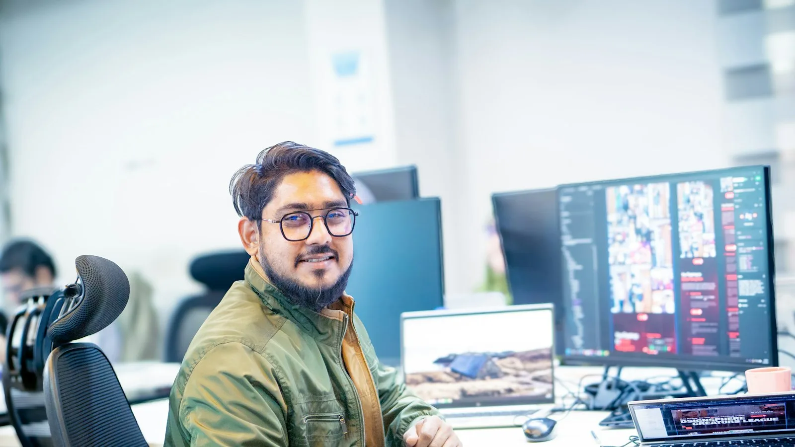 An offshore developer in India sits at his desk in front of two monitors in an open office.