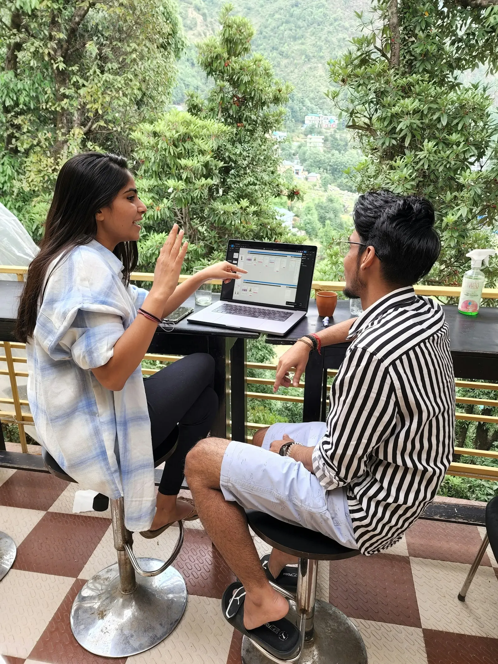 Two offshore developers in India go over work on a laptop at a café table.