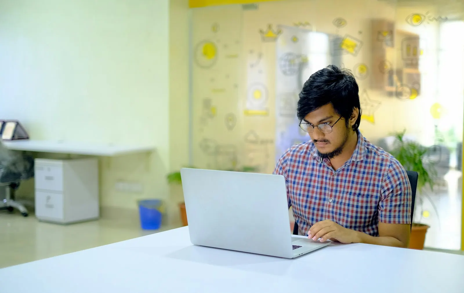 An offshore developer in India works on a laptop at a bright desk.