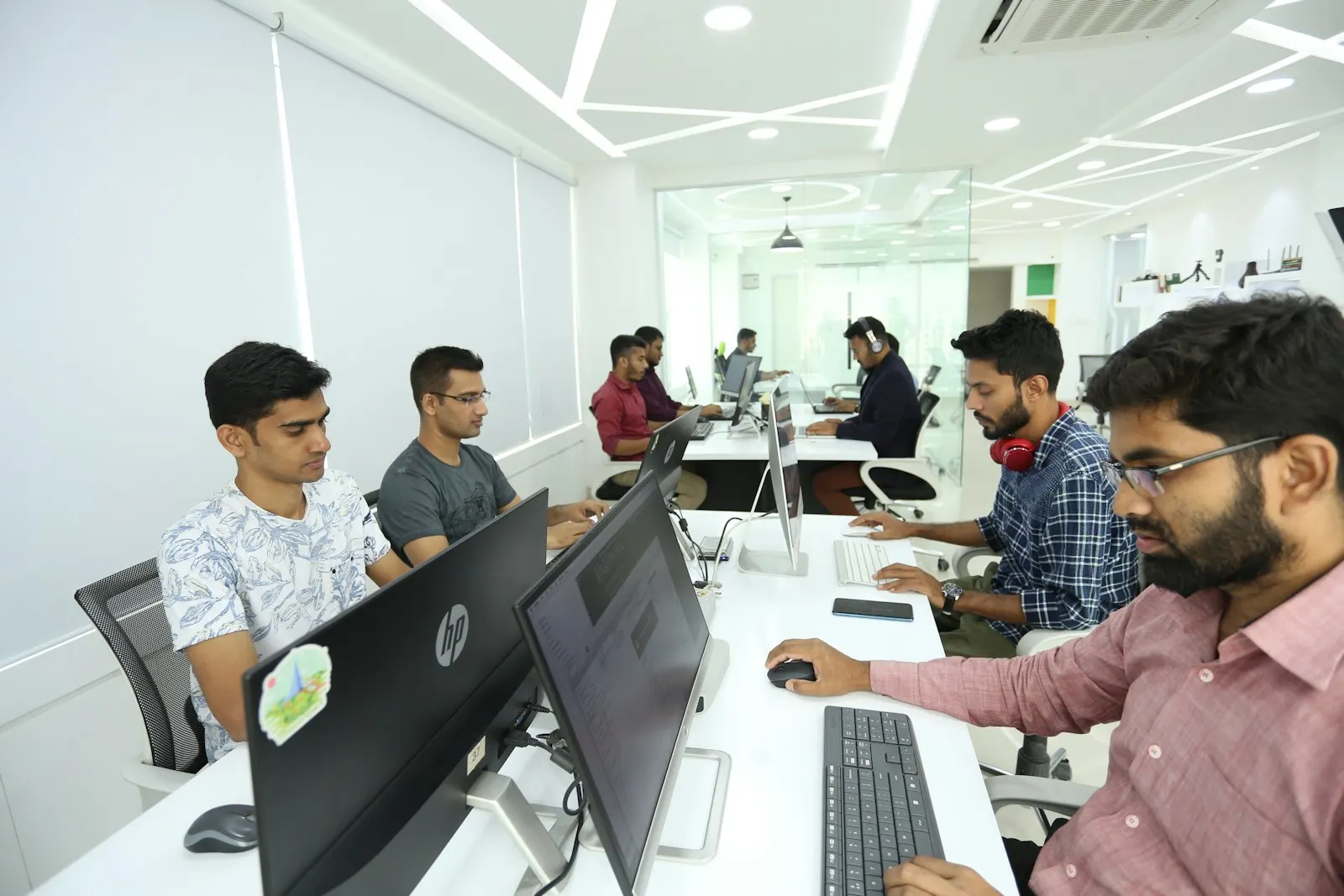 Offshore developers in India work side by side at desktops in a long, bright office.