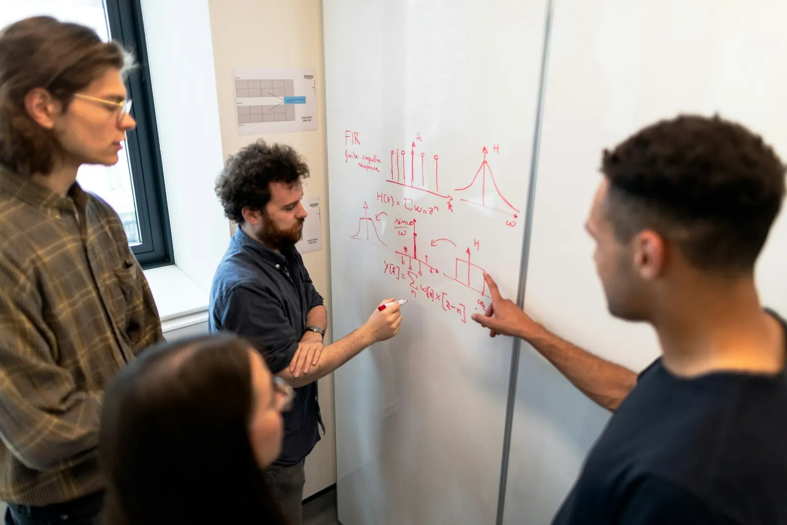 Engineers sketch a system on a whiteboard together.
