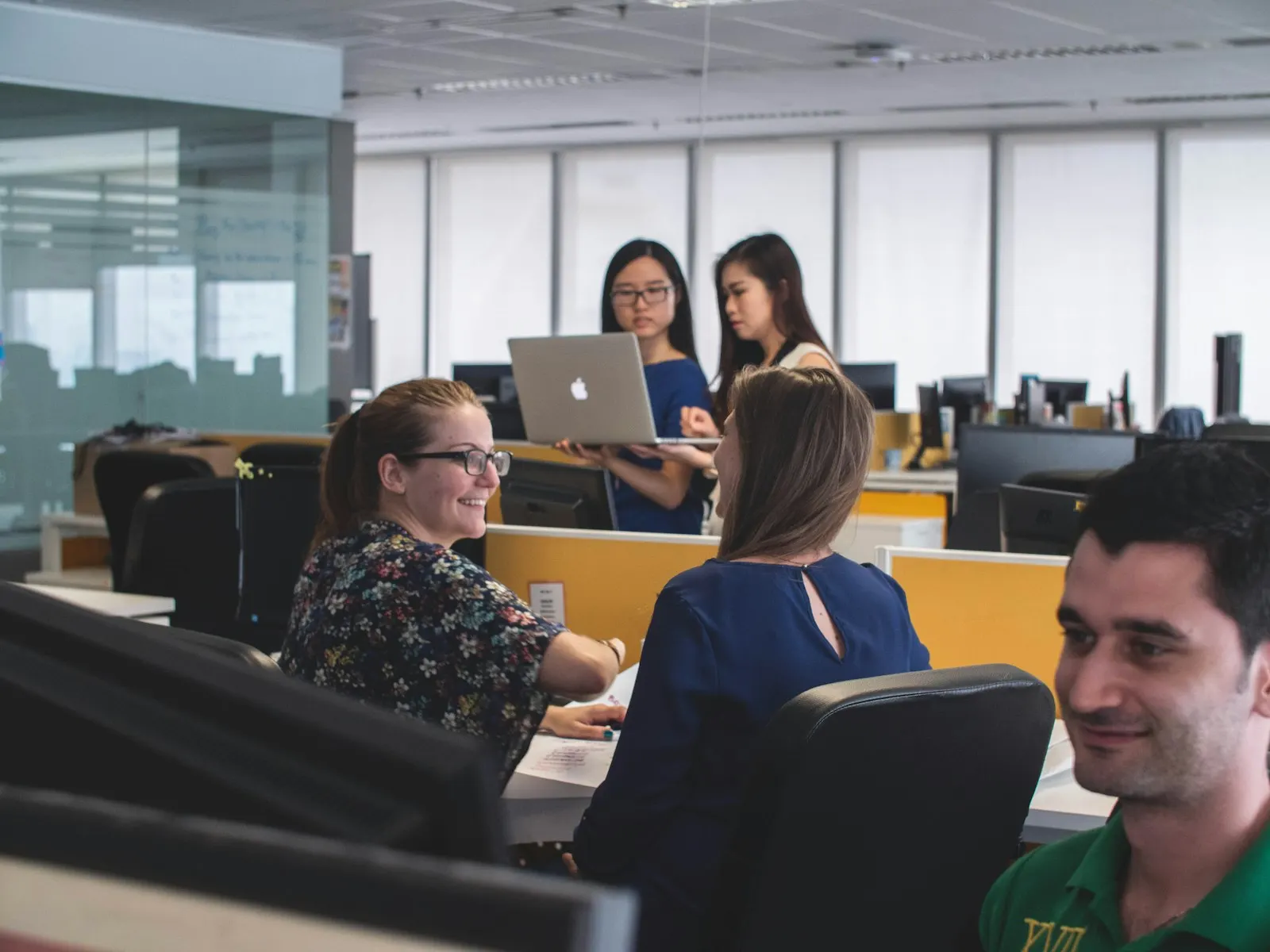 A dedicated development team sitting together at their desks in a bright office, laptops open.