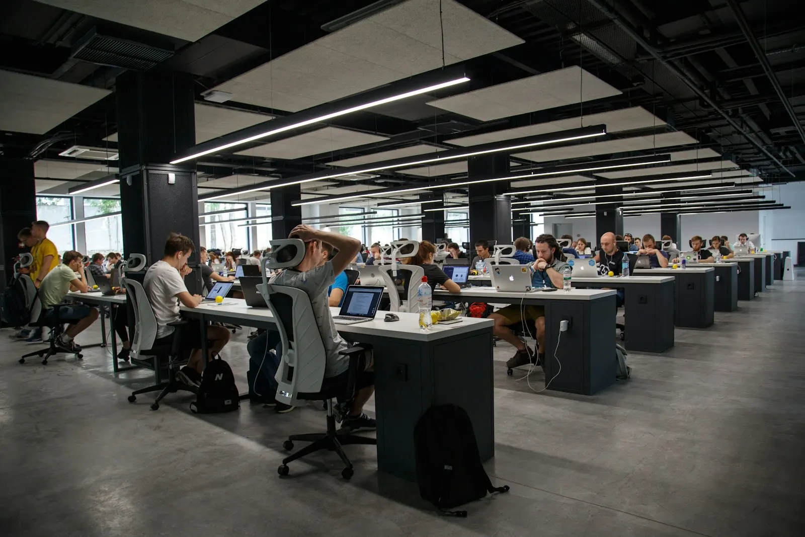 A dedicated development team at work in a large open-plan studio, rows of engineers at laptops and monitors.