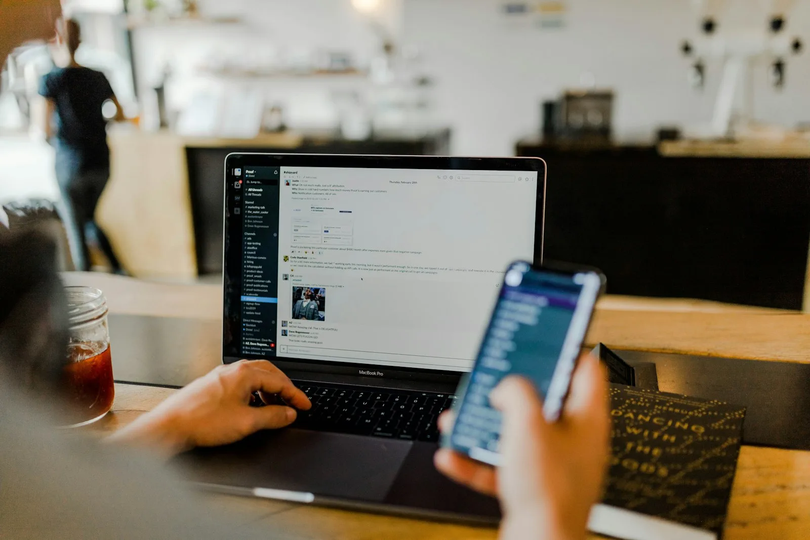 A hired QA Engineer checks an app on a phone beside a laptop running the same build.