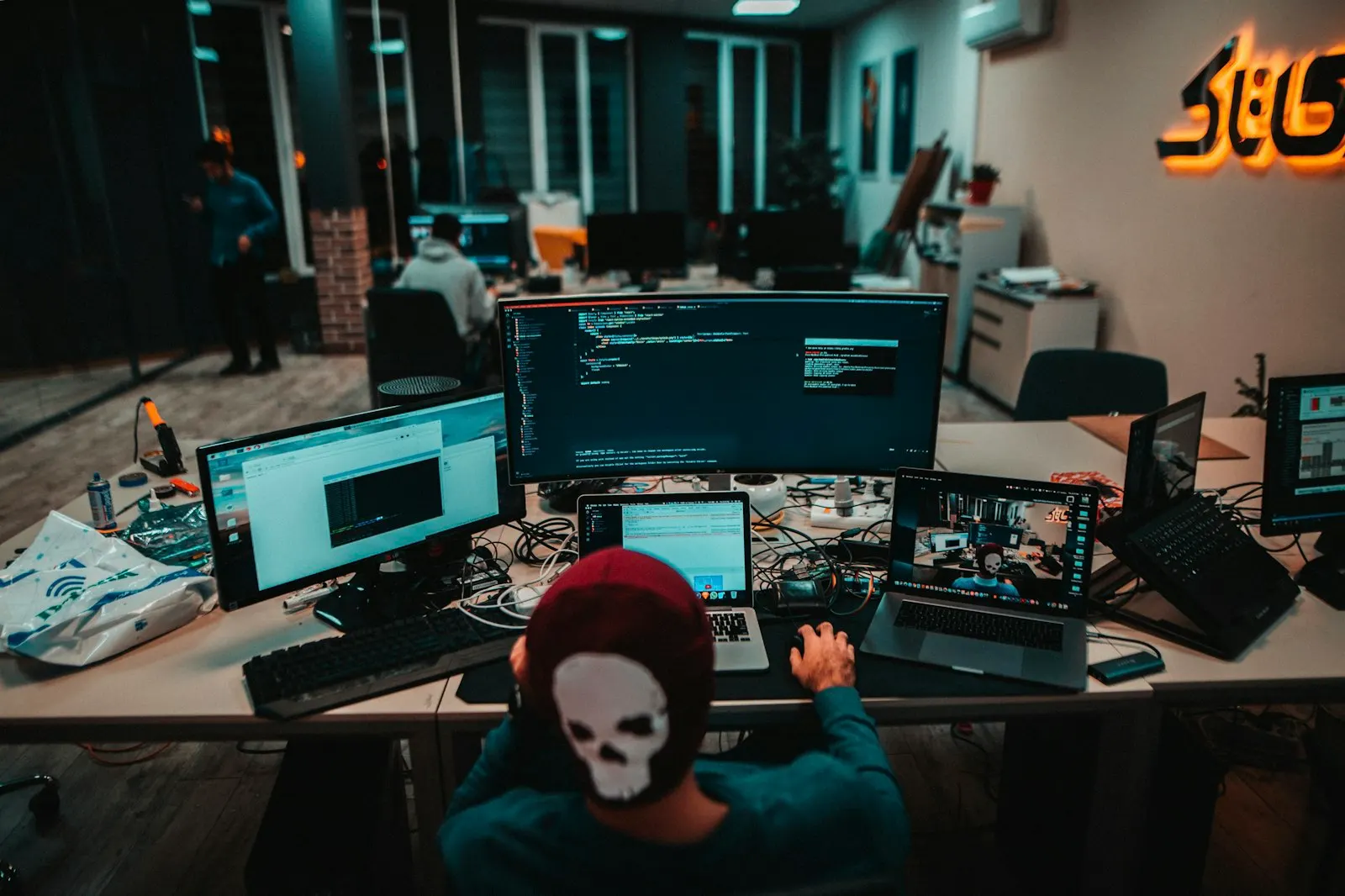 DevOps Engineers at work across rows of screens in a dimly lit operations room.