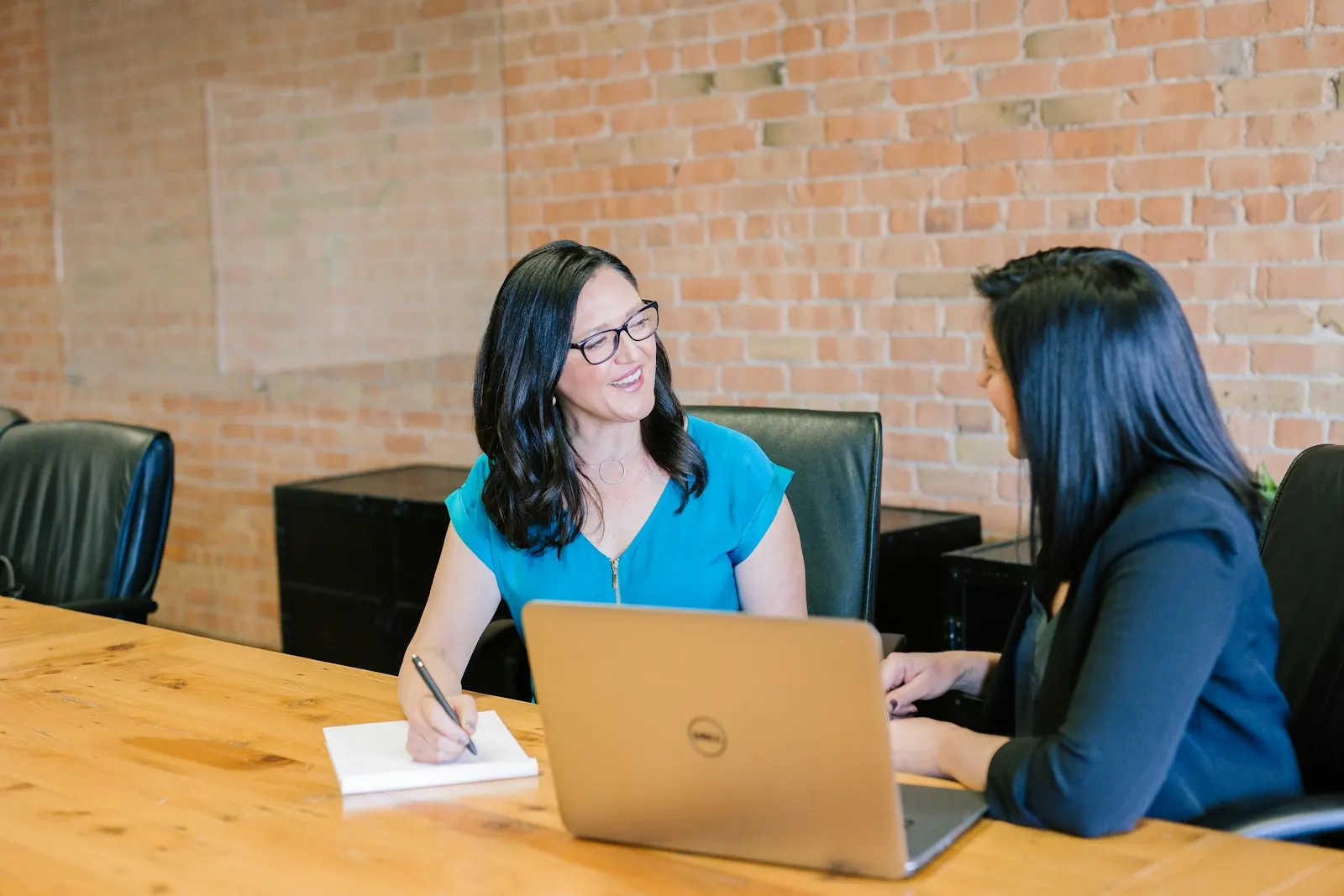 A hiring conversation with a specialist developer across a table, a laptop open between them.