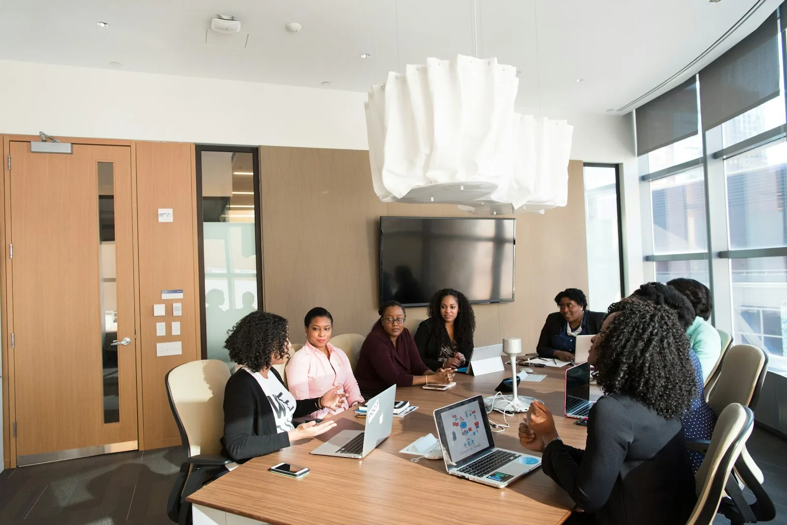 A leadership team planning global capability center services around a conference table with laptops open.
