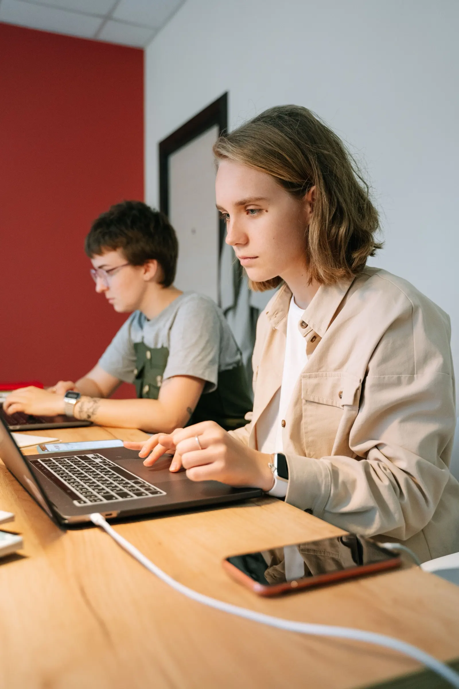 A teammate concentrates on her laptop at a shared desk.