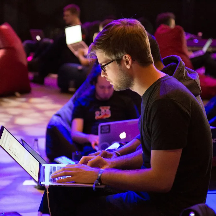 A developer coding on a laptop late in a dimly lit room
